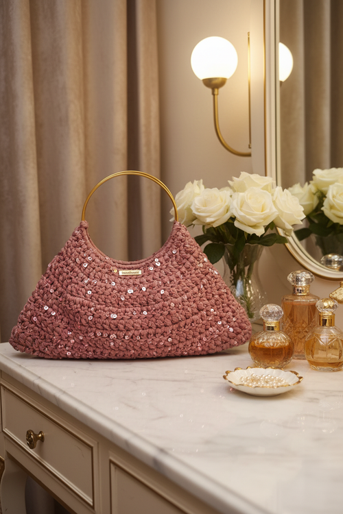 Borsa crochet rosa su tavolo in marmo con rose bianche